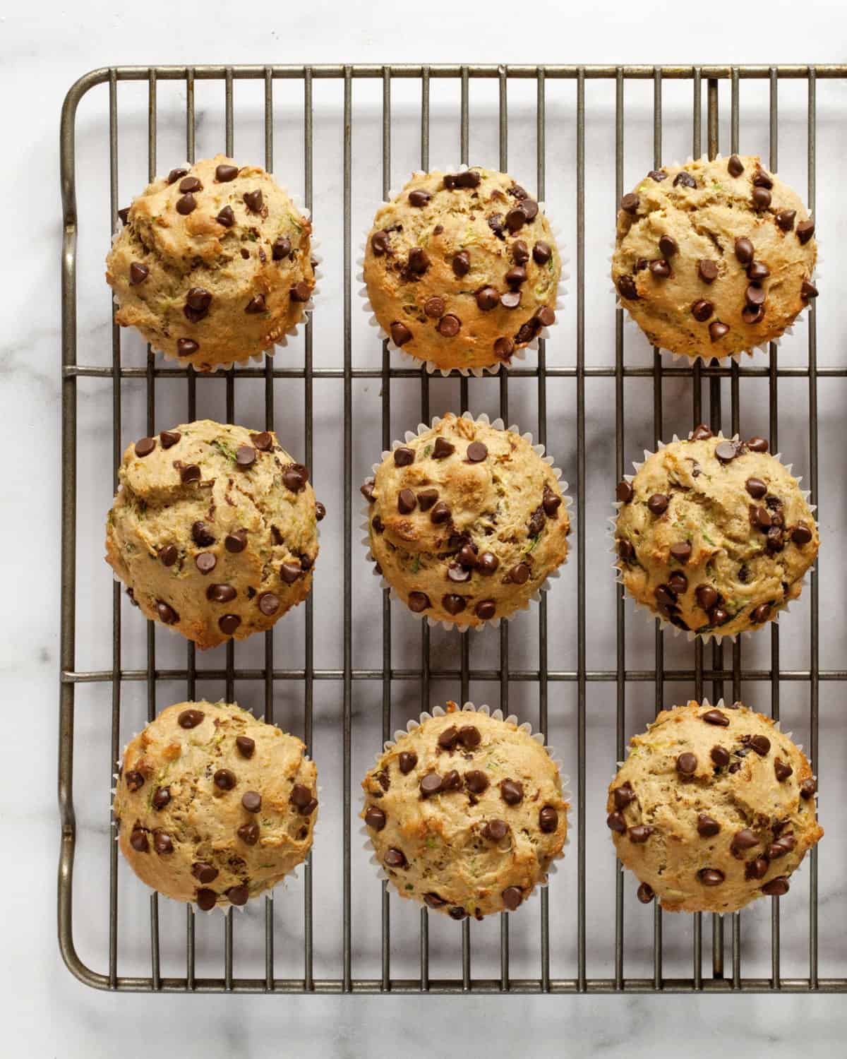 Nine zucchini muffins on a wire rack.