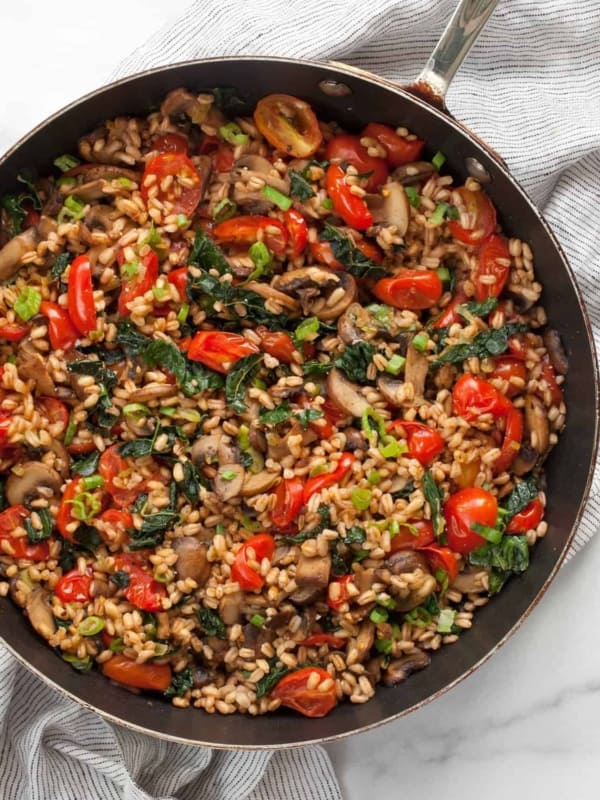 Mushroom farro with tomatoes and kale in a skillet.