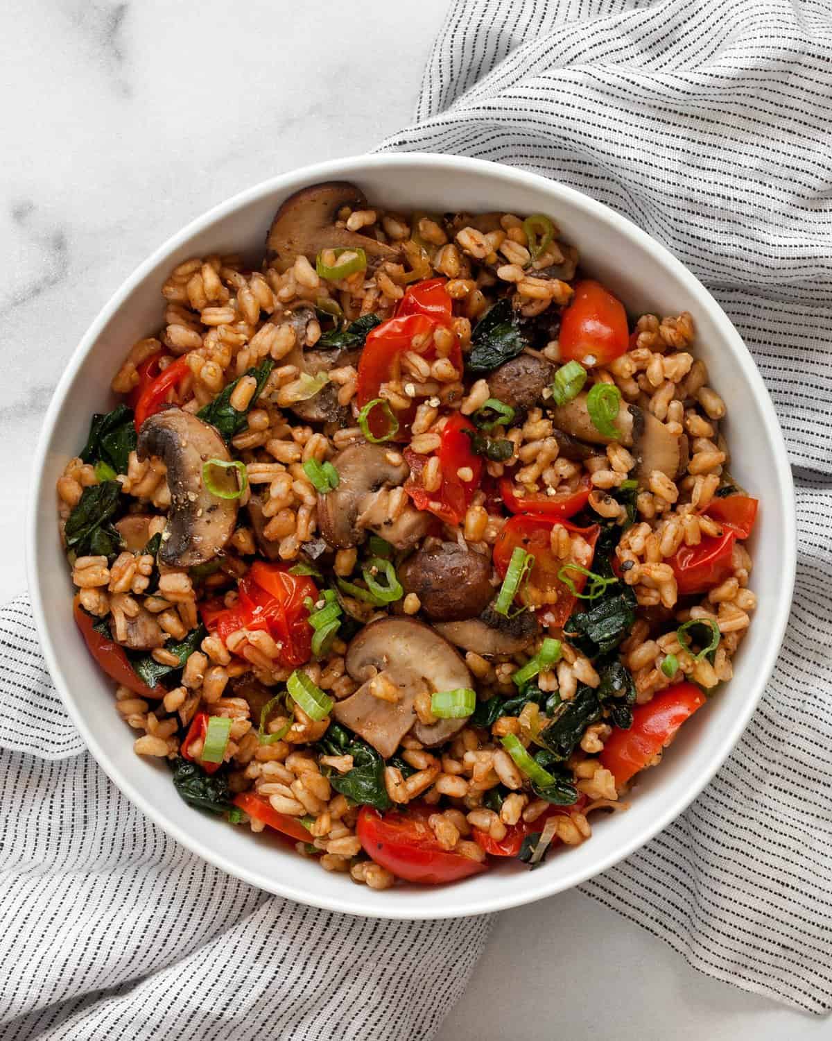 Mushroom farro with tomatoes and kale in a bowl.