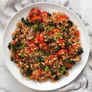 Mushroom farro with tomatoes and kale on a plate.