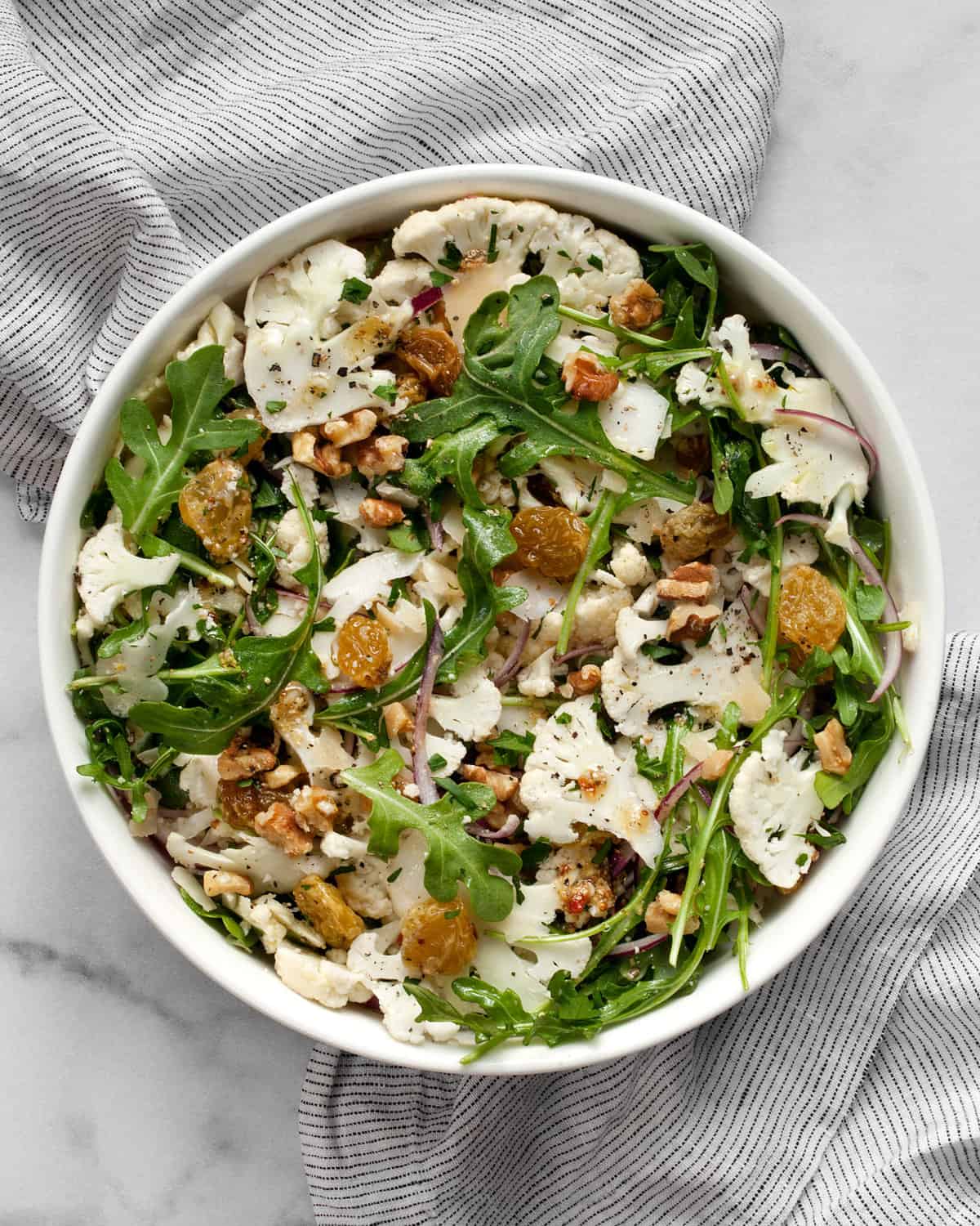 Salad with sliced cauliflower and arugula in a bowl.