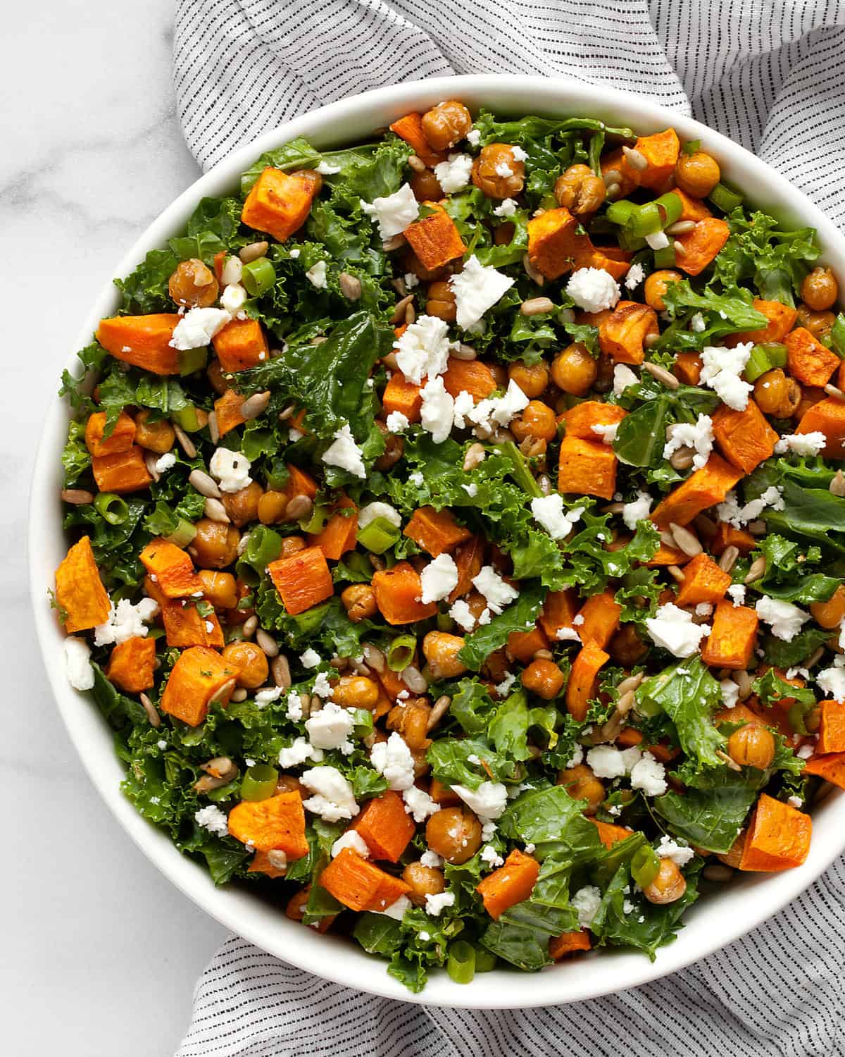 Kale salad with roasted sweet potatoes and chickpeas in a bowl.