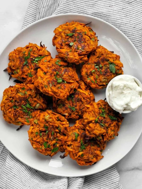 Baked sweet potato fritters on a plate with Greek yogurt.