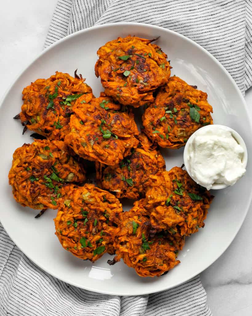 Baked sweet potato fritters on a plate with Greek yogurt.