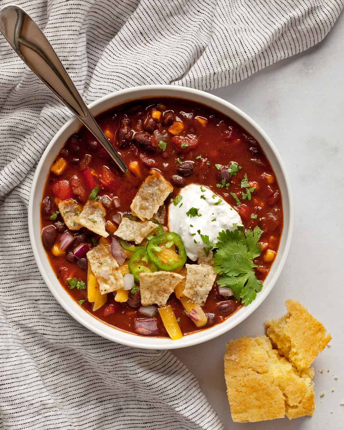 Bowl of balck bean chili with a piece of torn cornbread.