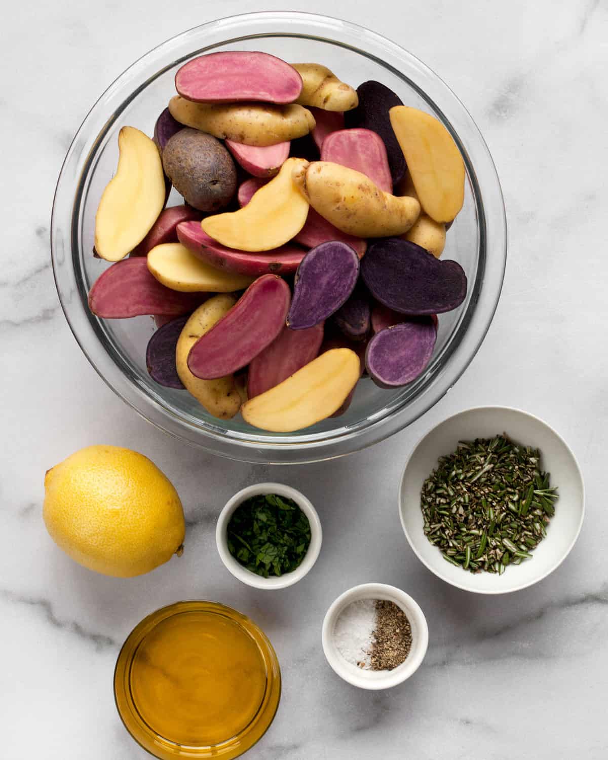 Ingredients including fingerling potatoes, lemon, olive oil, rosemary, parsley, salt and pepper.