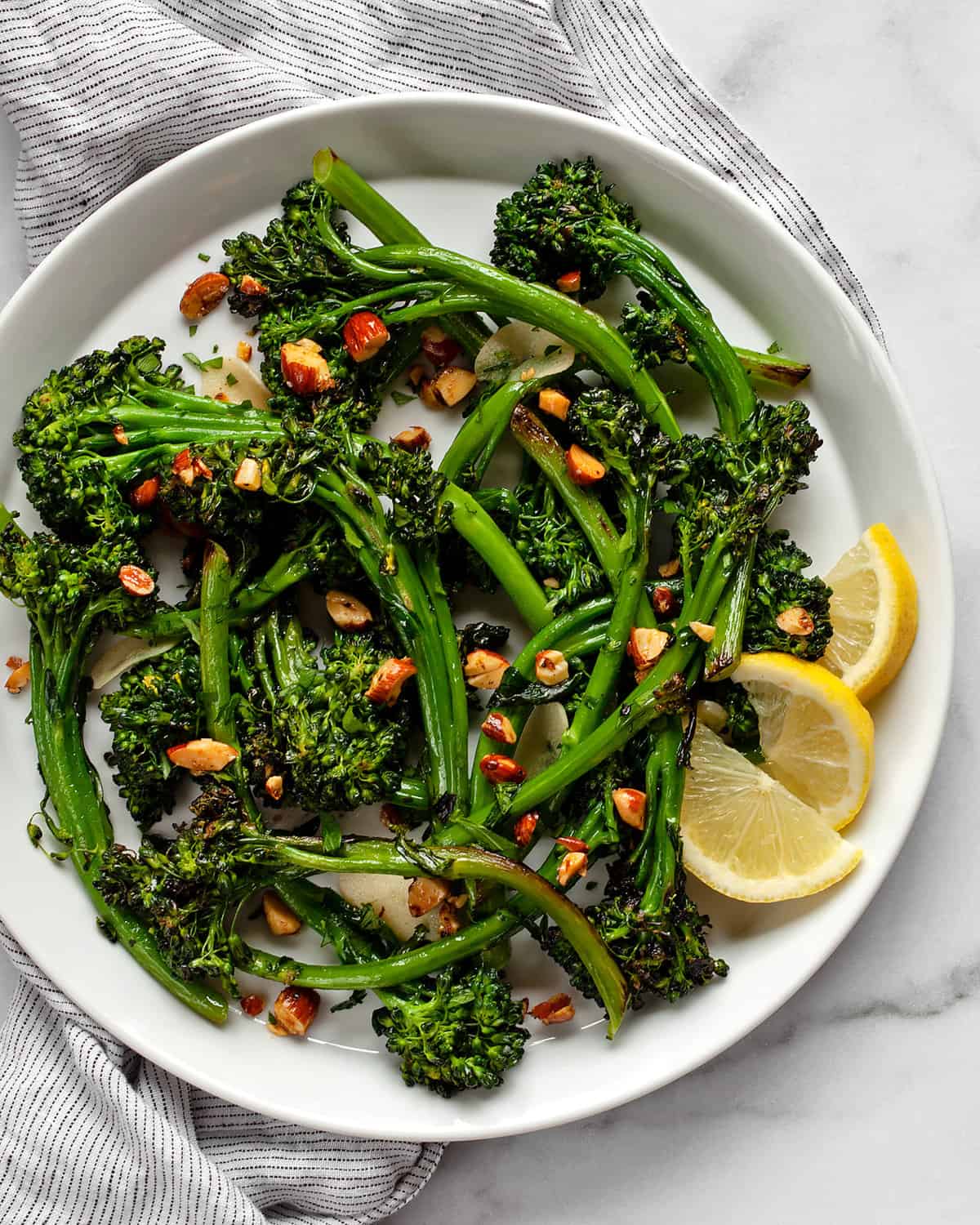 Broccolini piled on a plate with lemon wedges on the side.