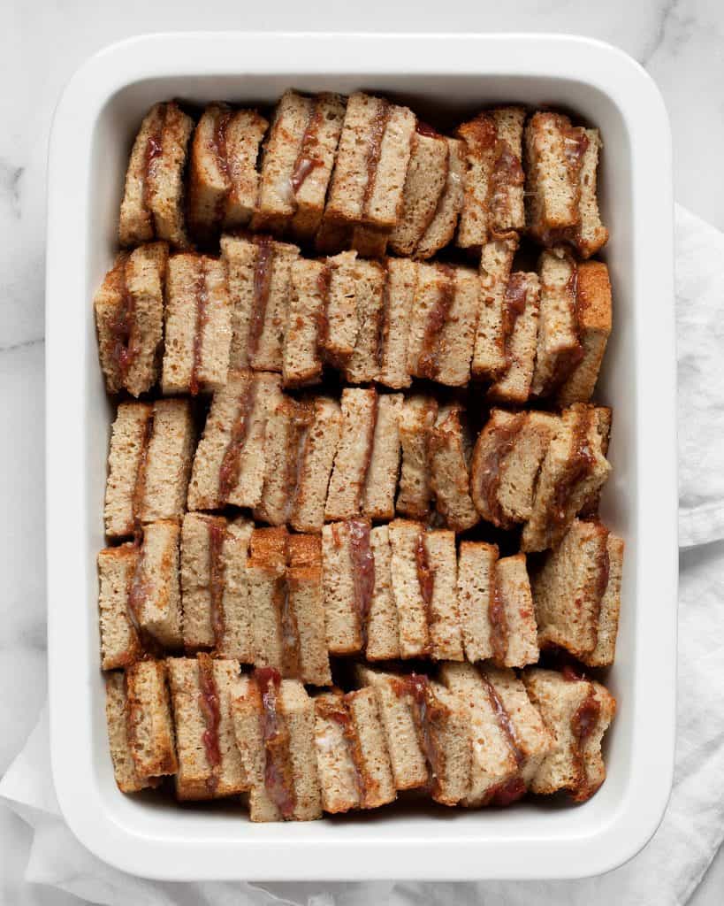 Assembling mini almond butter and jelly sandwiches in a baking dish