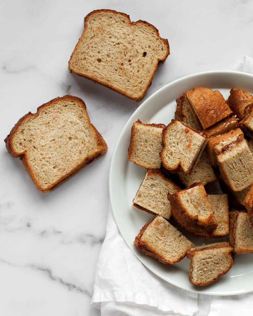 Making almond butter and jelly sandwiches and cutting them into quarters