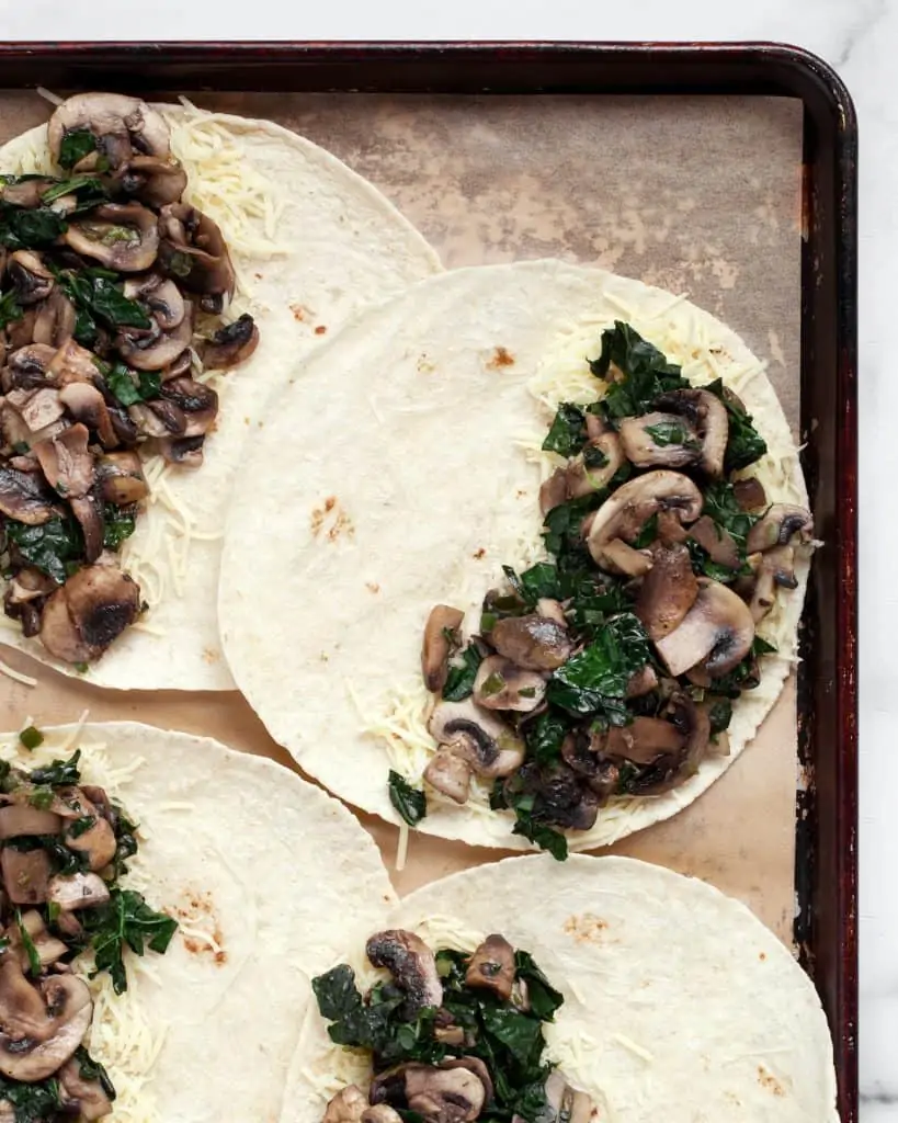 Assembling mushroom kale quesadillas on a sheet pan