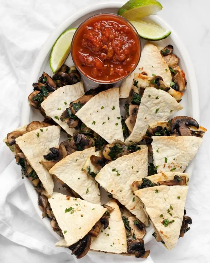 Baked Mushroom Kale Quesadillas on a plate with salsa and lime wedges