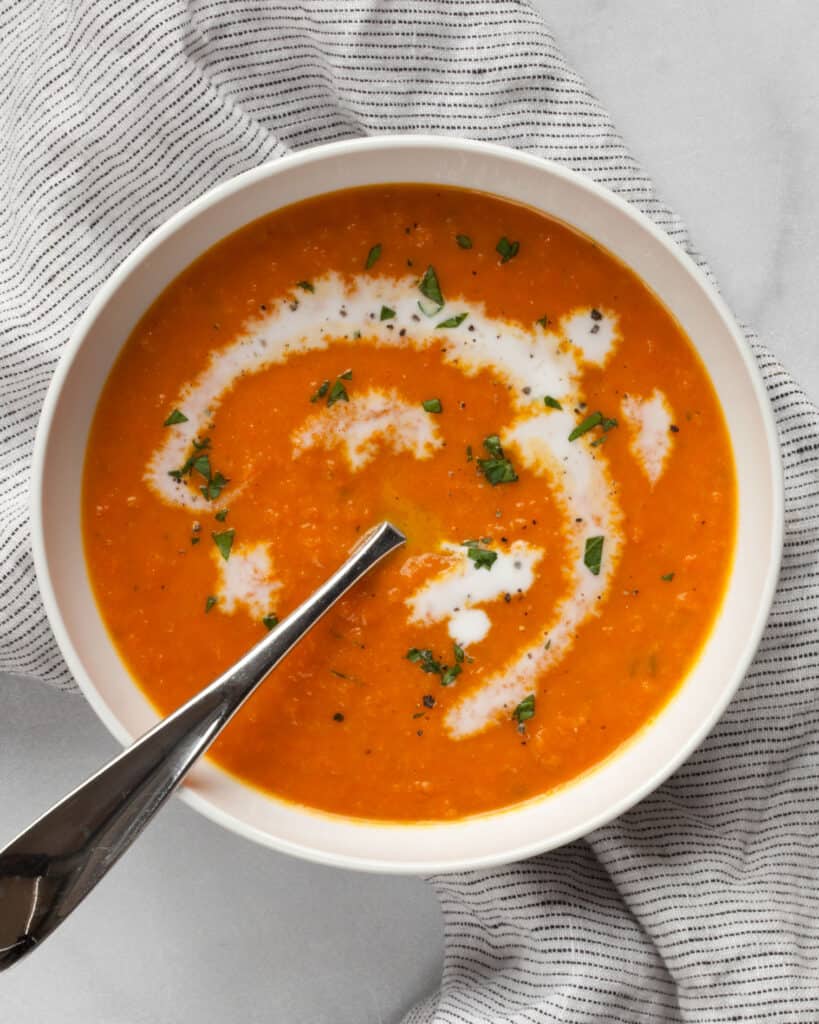 Bowl fo carrot ginger soup drizzled with coconut milk.