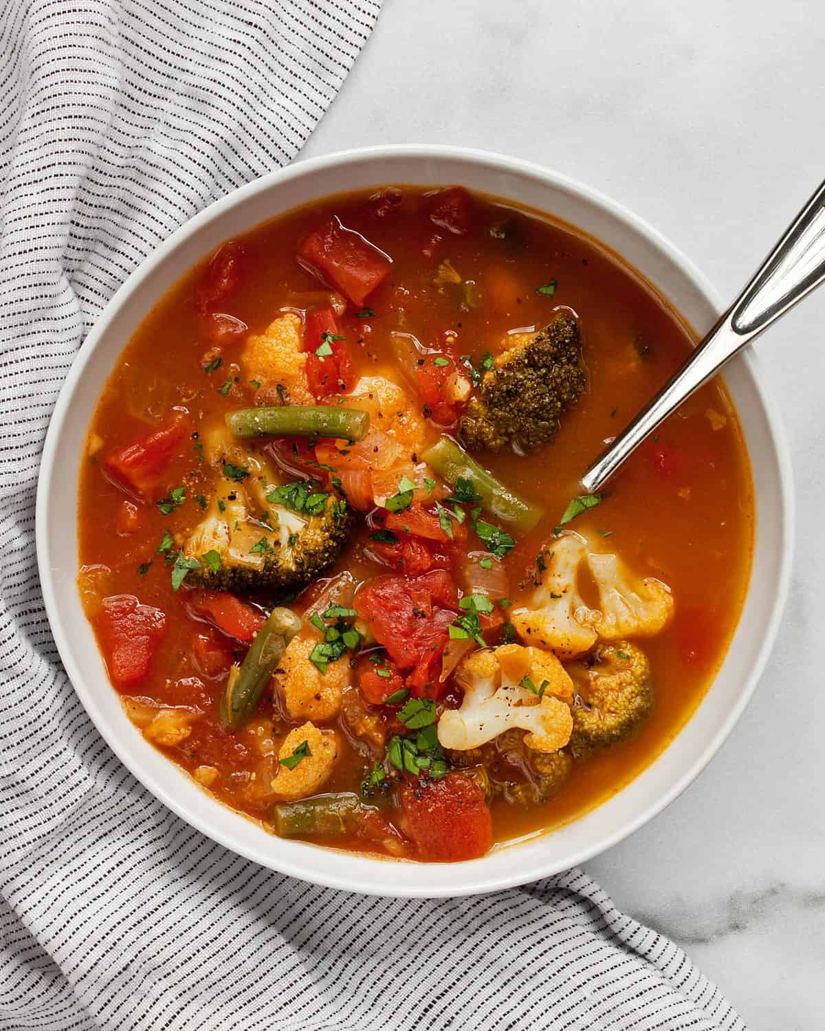 Vegetable soup with broccoli, greens beans and cauliflower in a bowl.