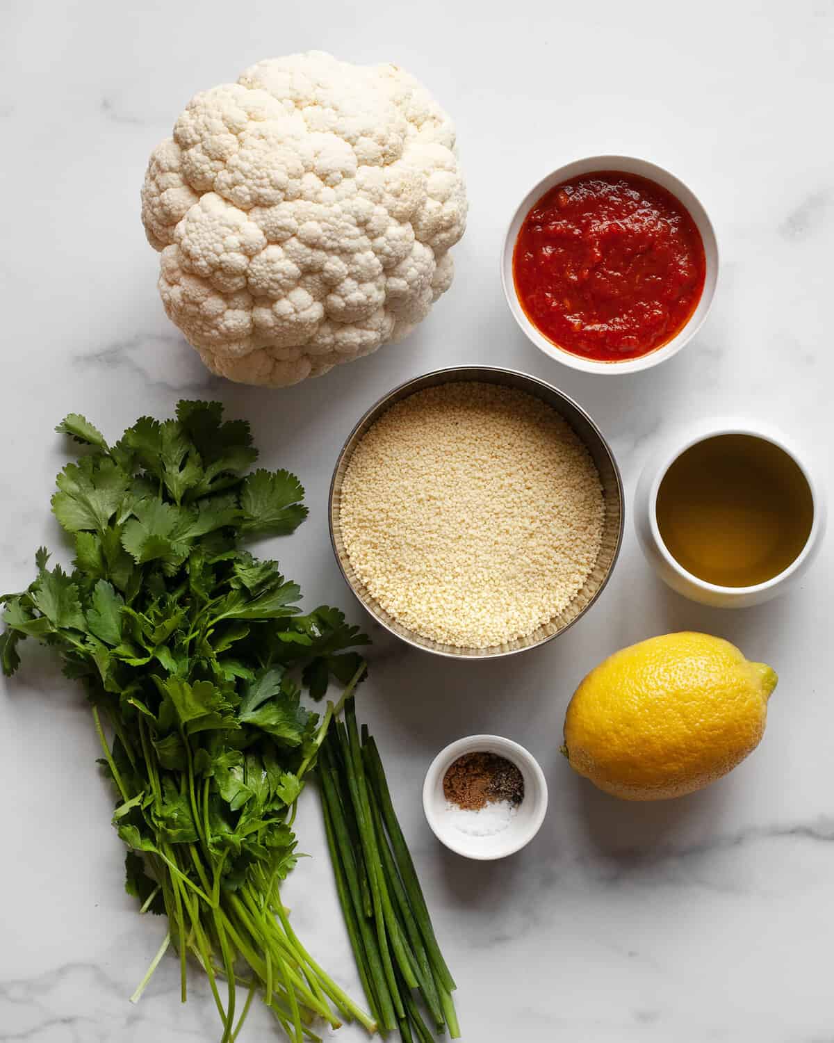 Ingredients including cauliflower, couscous, herbs, spices, harissa and olive oil. 
