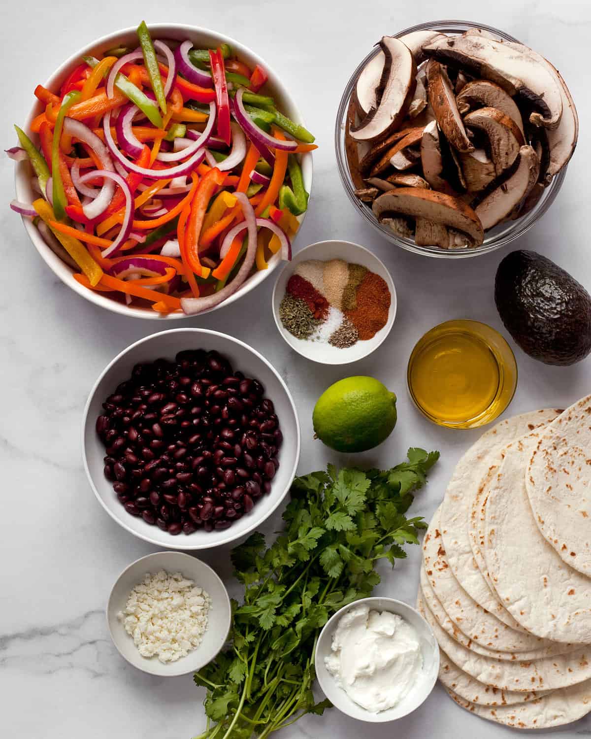 Ingredients including, peppeps, onion, portobello mushrooms, beans, cilantro, lime, tortillas and cheese.