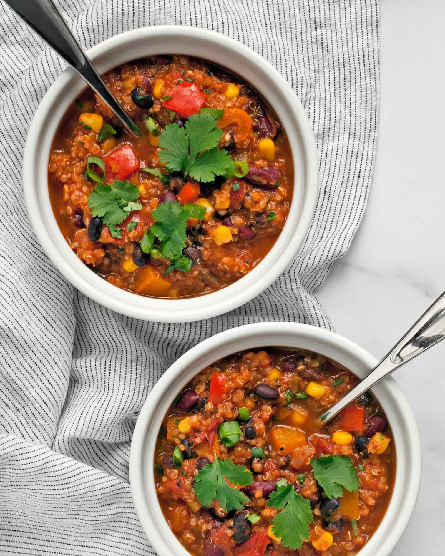 Two bowls of chili topped with cilantro and scallions