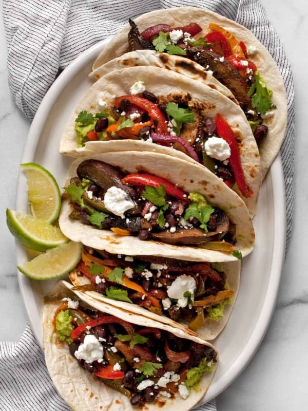 Five vegetarian fajitas arranged on an oval plate.