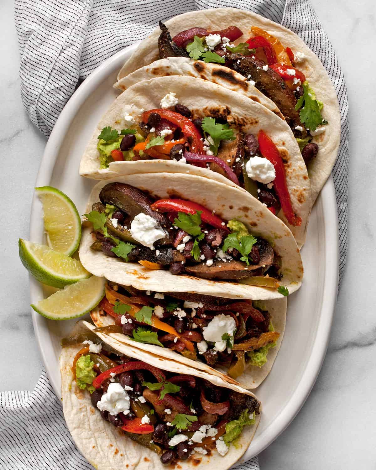 Five vegetarian fajitas arranged on an oval plate.