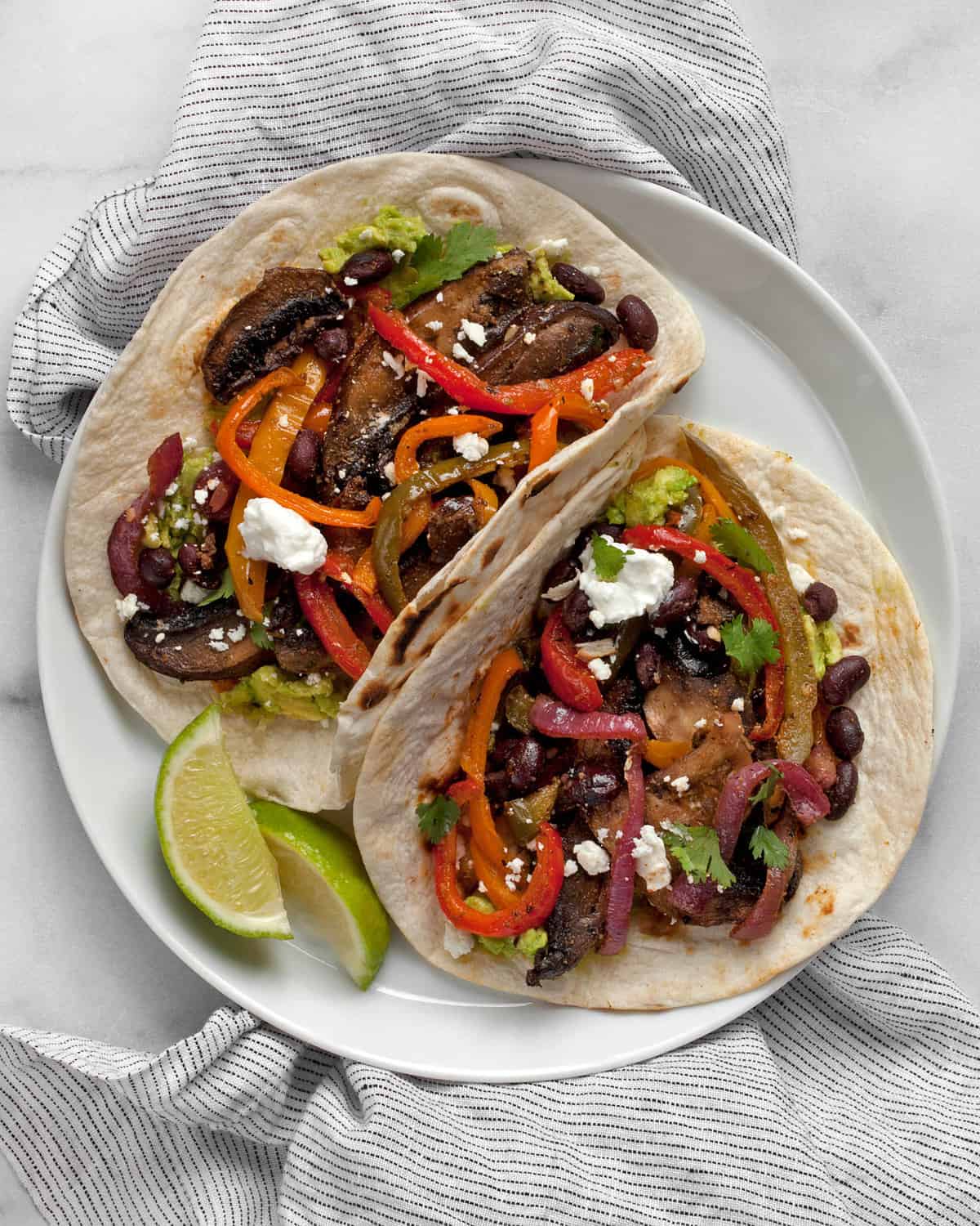 Two vegetarian fajitas side-by-side on a plate.