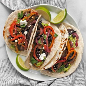 Three vegetarian fajitas on a plate.