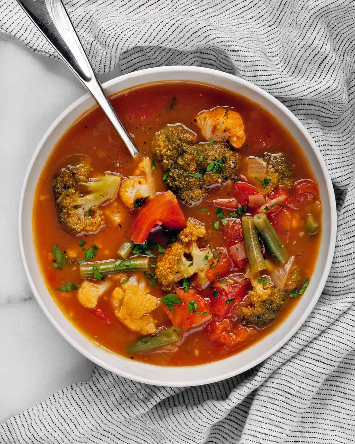 Vegetable soup with tomatoes, cauliflower and broccoli in a bowl.