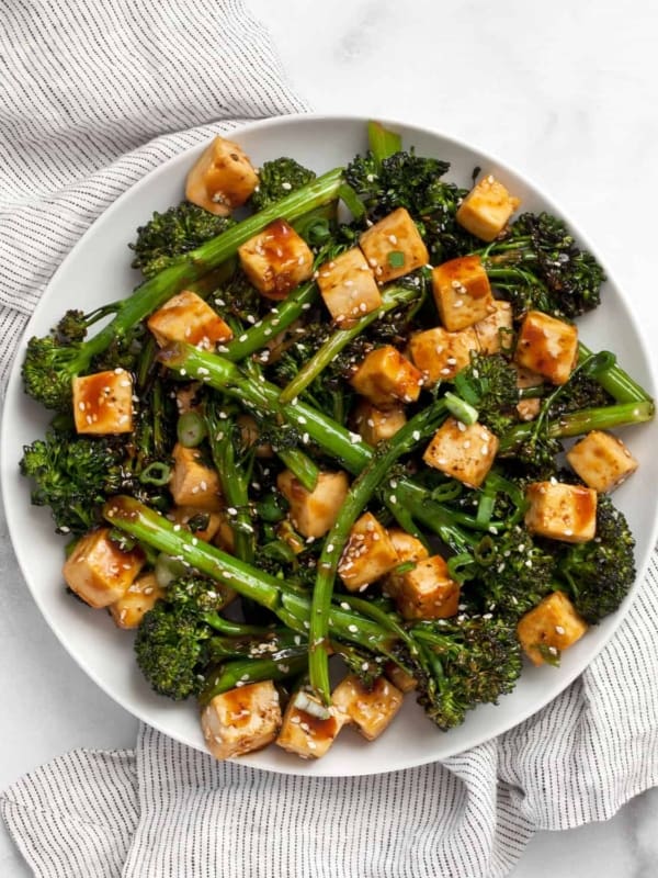 Baked tofu and broccolini with teriyaki sauce on plate.