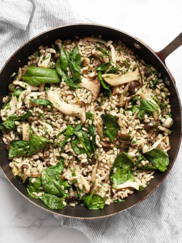 A skillet with barley, sautéed mushrooms and spinach.