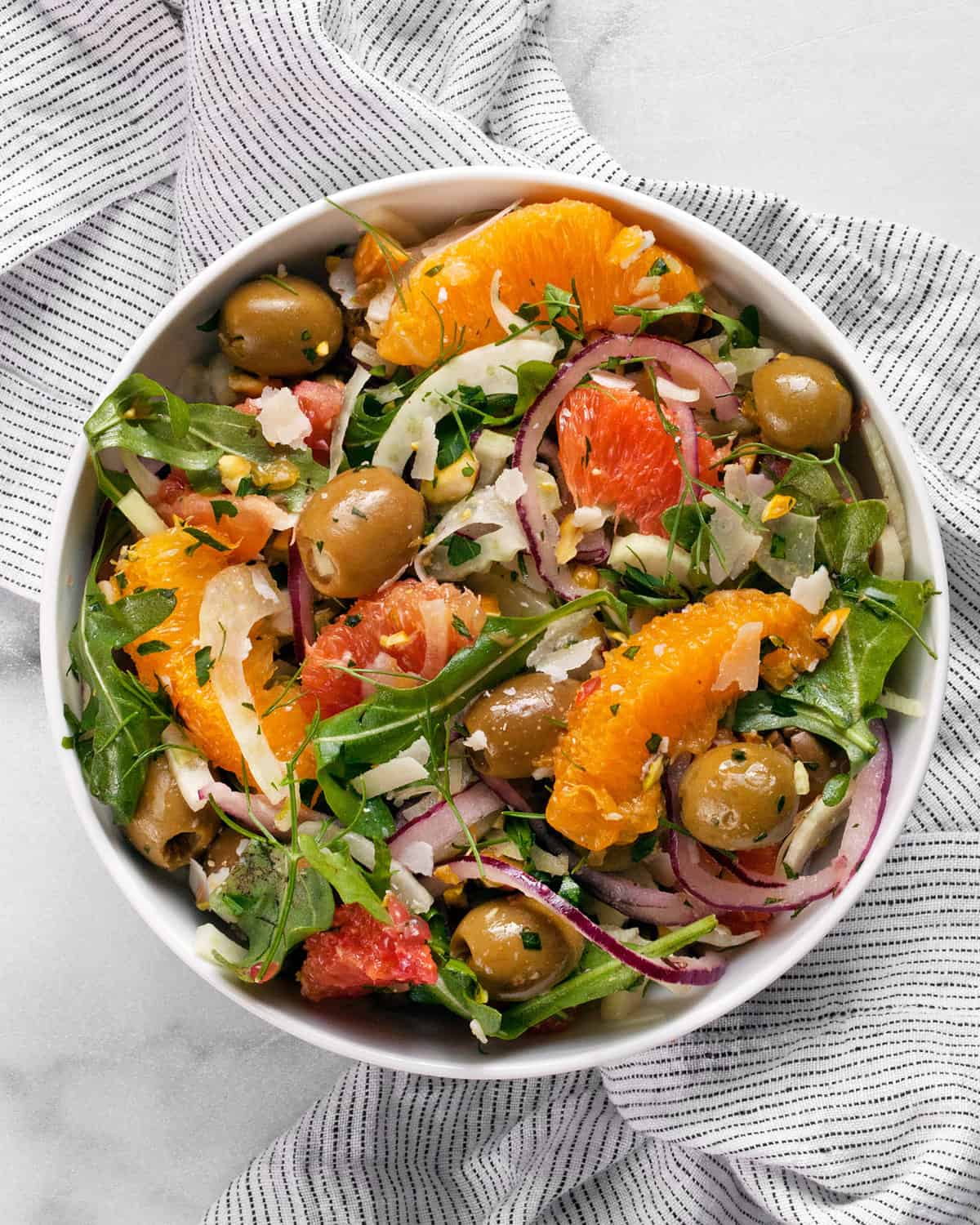 Orange salad with fennel and arugula in a small bowl.