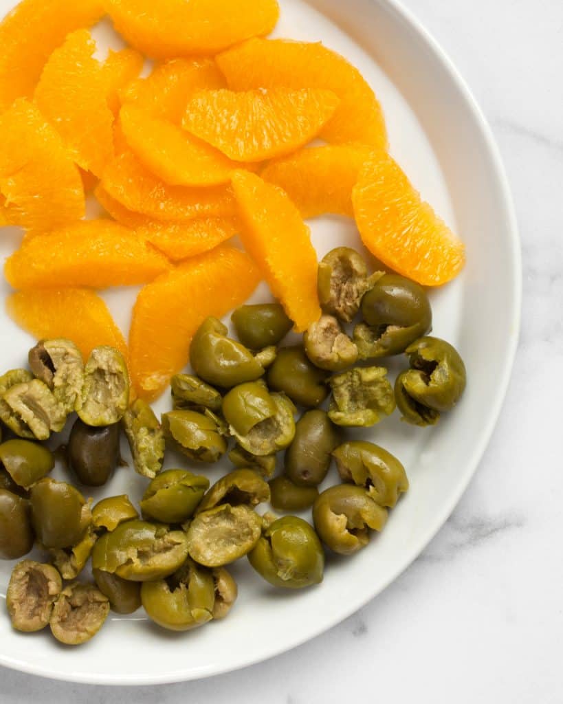Orange slices and green olives on a plate