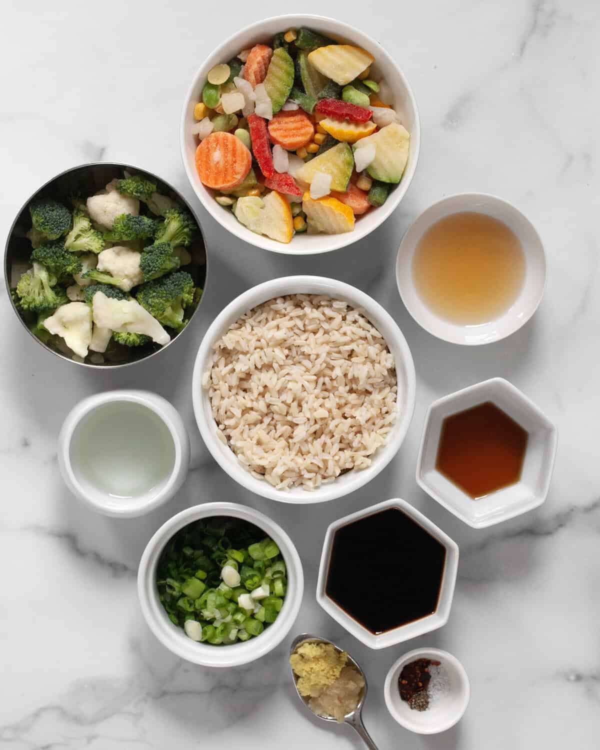 Ingredients including frozen veggies, cooked brown rice, rice vinegar, sesame oil, soy sauce, scallions, ginger, garlic and seasonings.