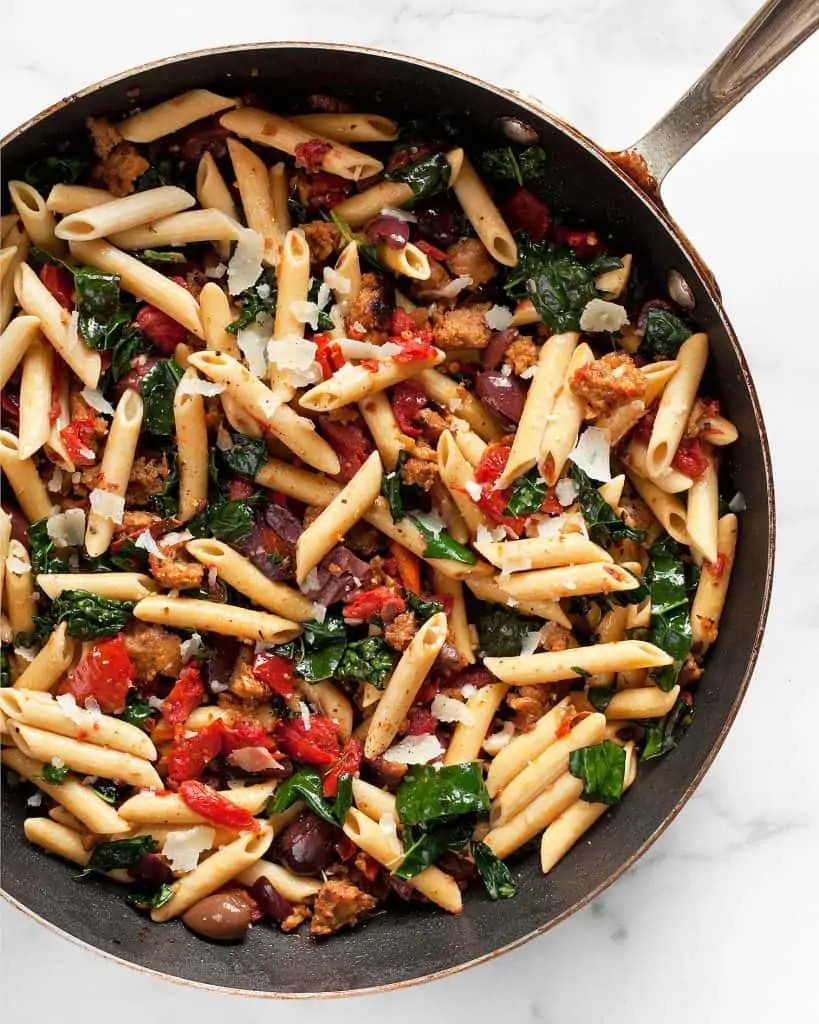Skillet with penne, tomatoes, olives, kale and sausage