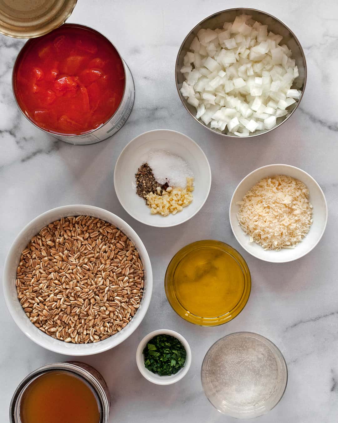 Ingredients including farro, canned tomatoes, onions, garlic, spices and broth