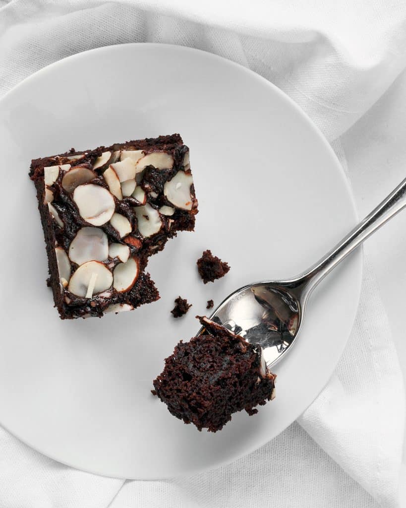 A slice of mocha almond cake on a plate with a fork