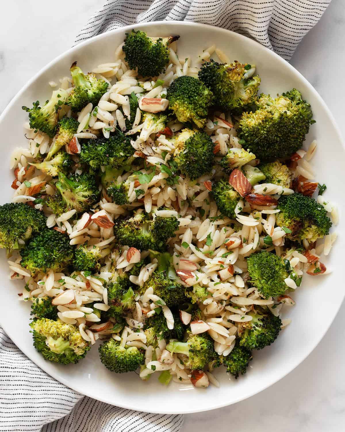 Orzo with roasted broccoli, almonds, lemon and garlic on a plate.