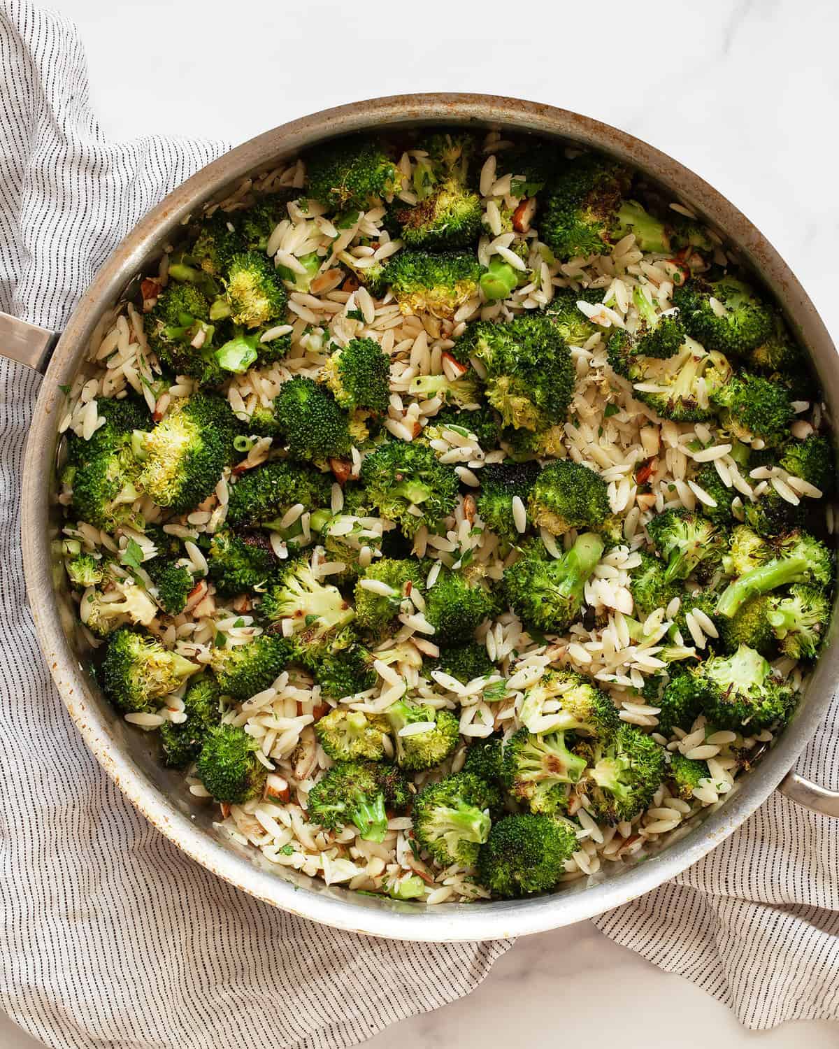 Orzo with roasted broccoli in a sauté pan.