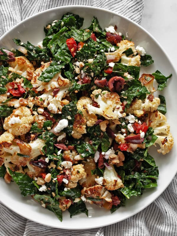 Roasted cauliflower kale salad with tomatoes and olives on a plate.