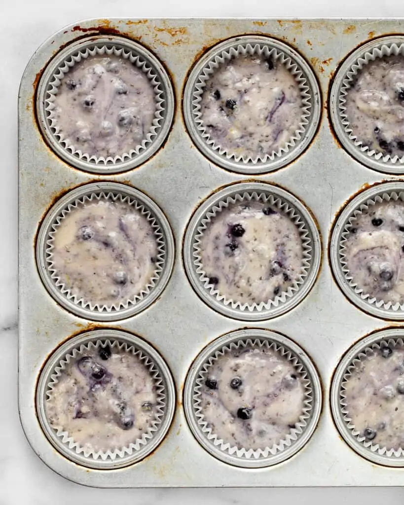 Blueberry muffin batter portioned into muffin pan