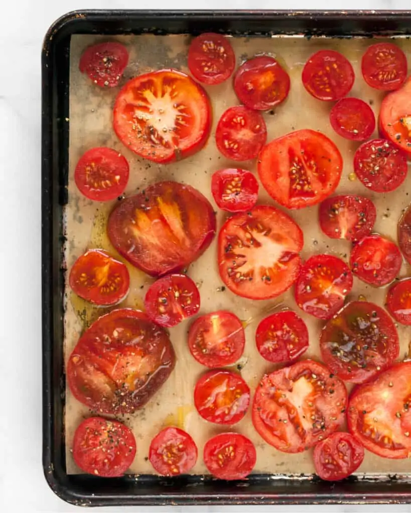 Raw sliced tomatoes on sheet pan drizzled with olive oil