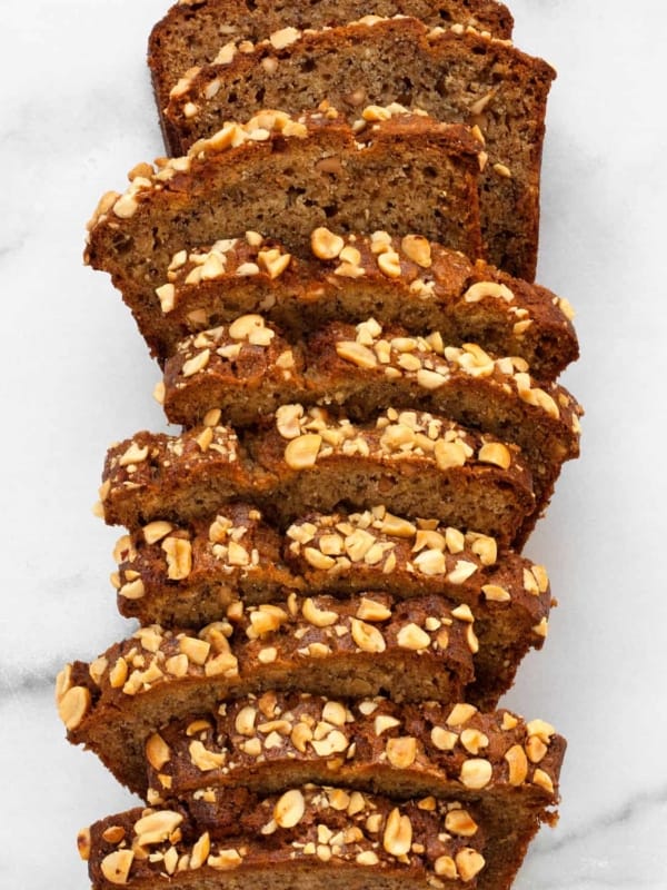 Slices of peanut butter banana bread with chopped nut topping.