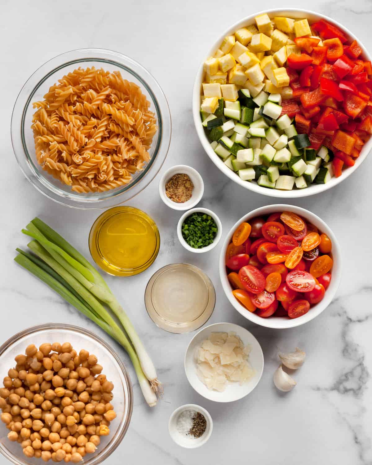 Ingredients including chickpea pasta, vegetables, chickpeas, vinegar, olive oil, garlic and scallions.