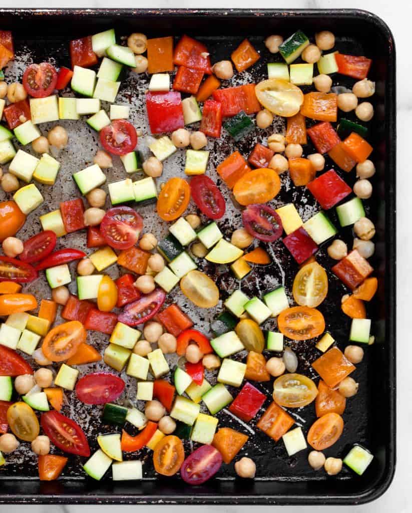 Diced zucchini and squash, halved cherry tomatoes and chickpeas on a sheet pan