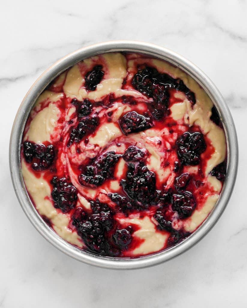 Cake batter in a pan topped with blackberries