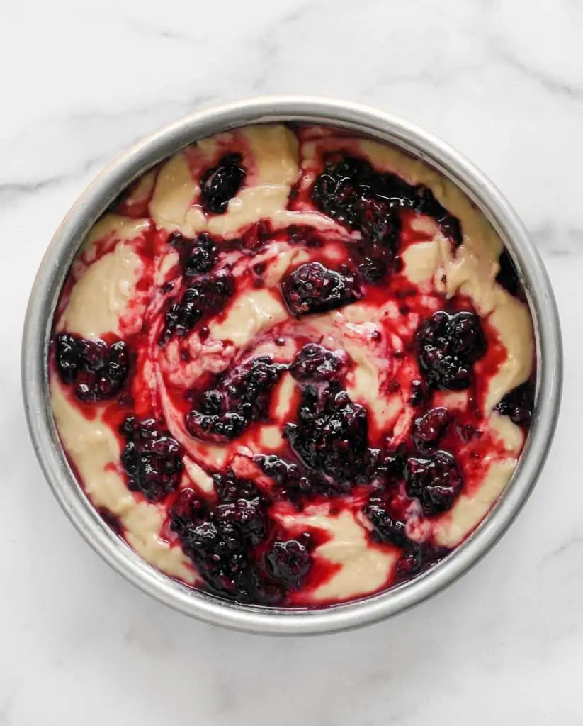 Cake batter in a pan topped with blackberries