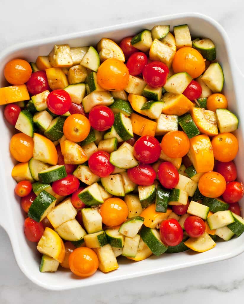 Tomatoes, zucchini and squash tossed in balsamic marinade in baking dish