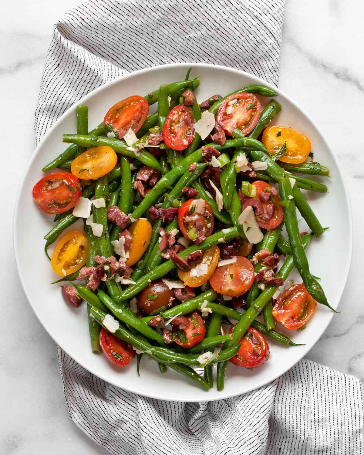 Tomato, olive, green bean salad on a plate.