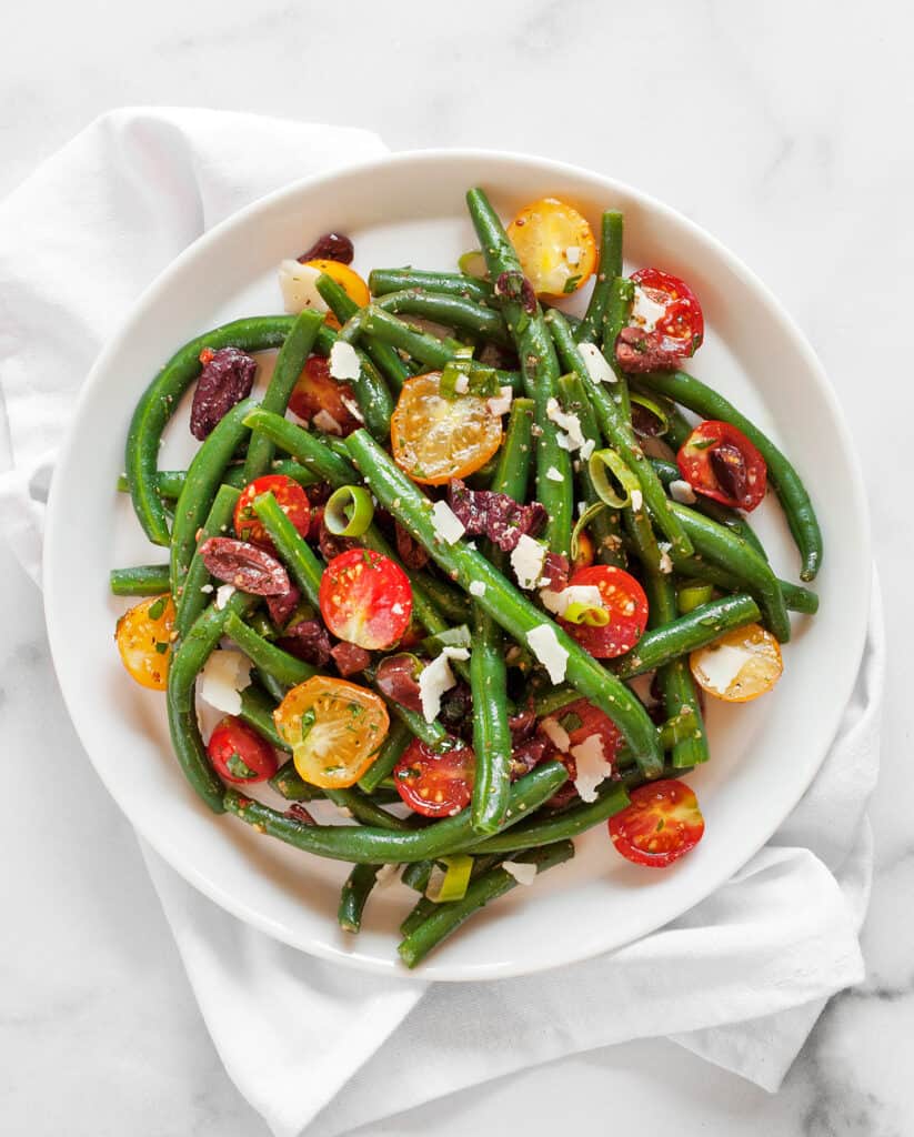 Salad with green beans, tomatoes and olives on a plate.