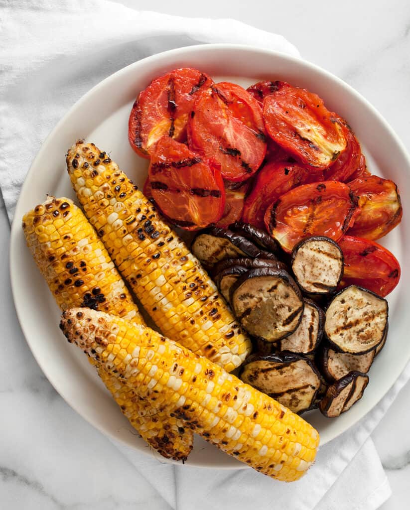 Grilled ears of corn with tomatoes and eggplant