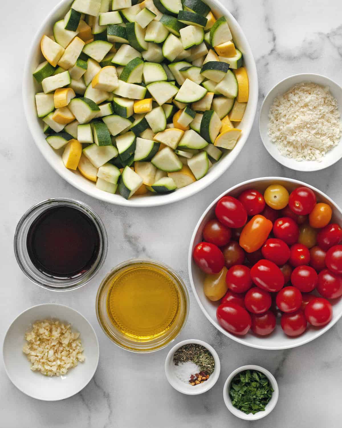Ingredients including zucchini, squash, tomatoes, balsamic vinegar, olive oil, garlic, spices and parmesan.