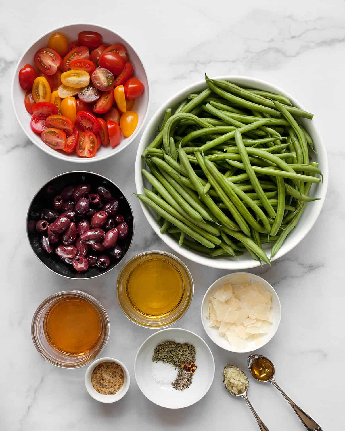 Ingredients including green beans, tomatoes, olives, parmesan, red wine vinegar, mustard, garlic and scallions.