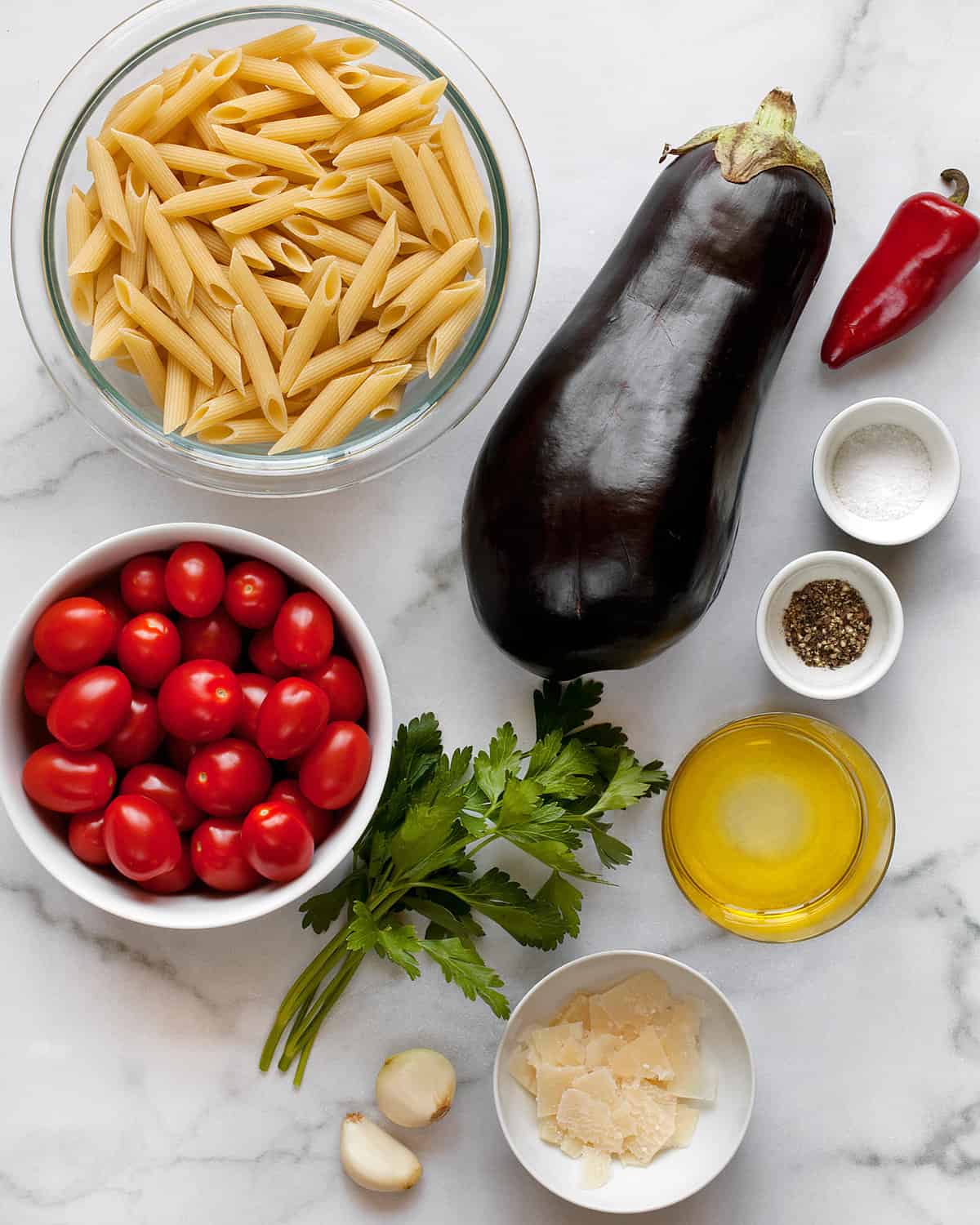Ingredients including penne, eggplant, fresno chili, tomatoes, garlic, parsley, olive oil, salt and pepper